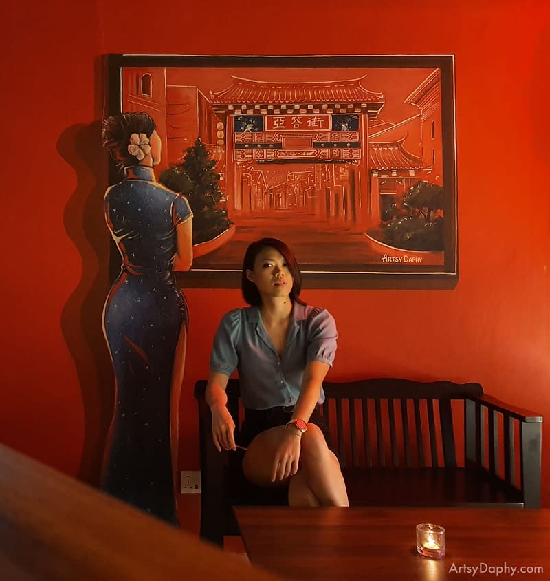 Girl posing with a mural of an oriental woman looking at Carpenter Street painting inside a hidden bar